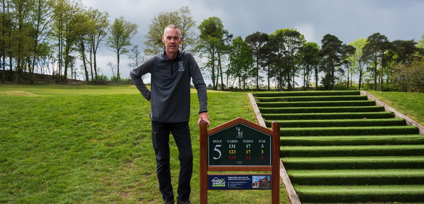 A sponsor stood beside the tee sign carrying their panel.